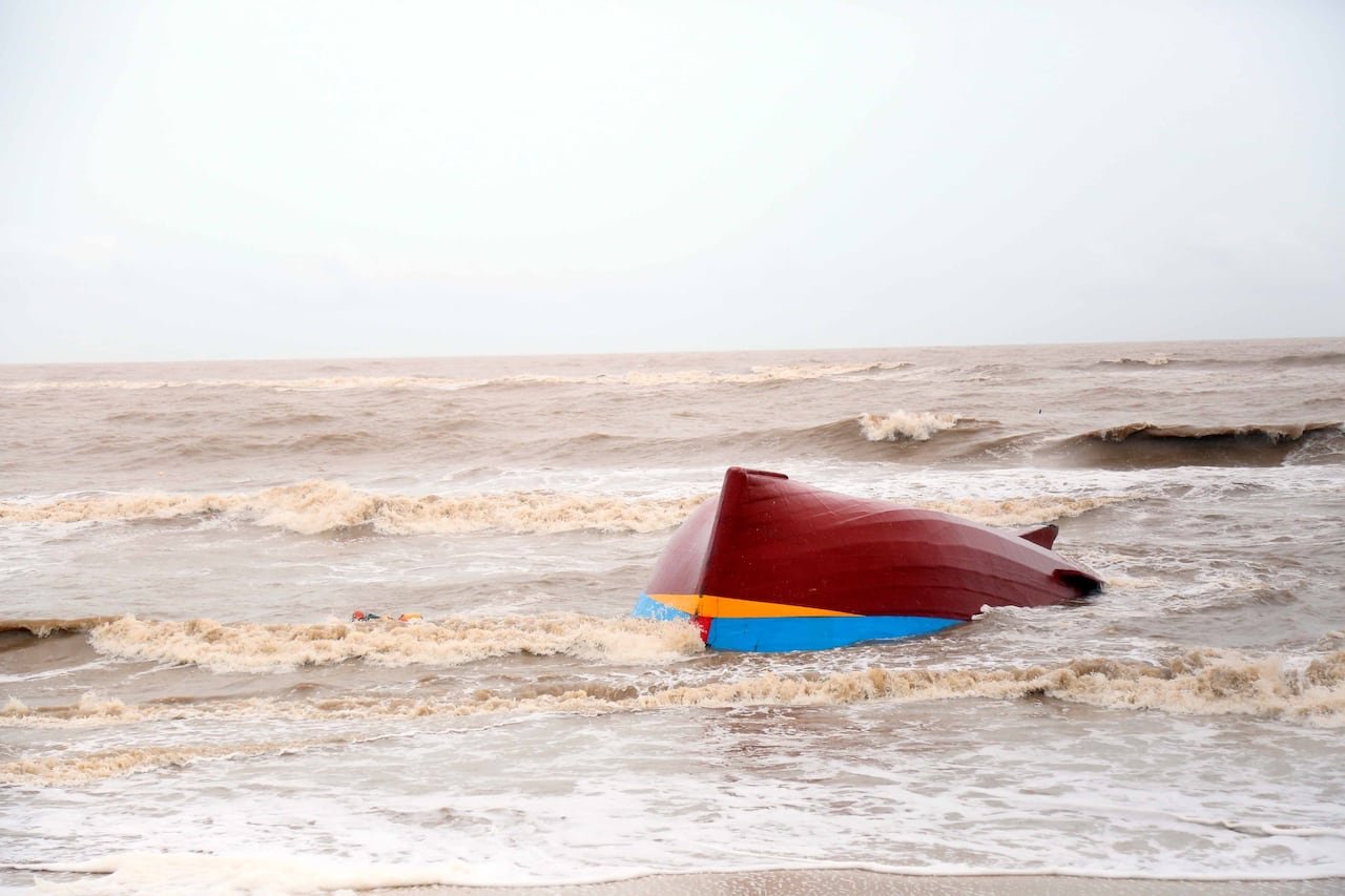 default-247 A small red boat is overturned in a body of water with significant waves.