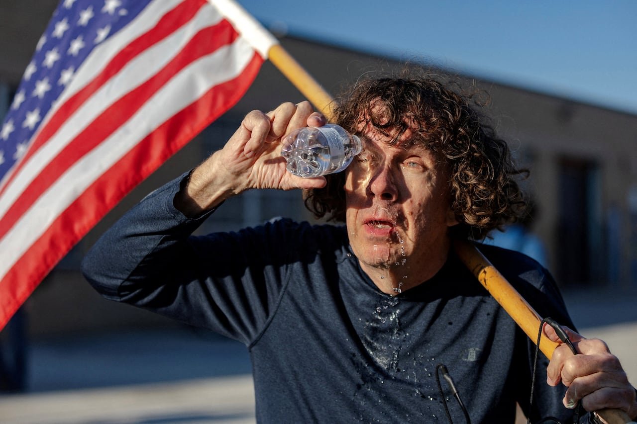default-265 A man flushes a chemical irritant out of his eyes while holding an American flag.