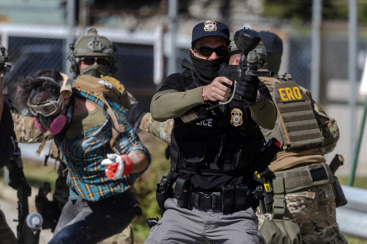 default-266 Authorities arrest a protester in the back as a federal agent holds what looks to be a projectile weapon at others.