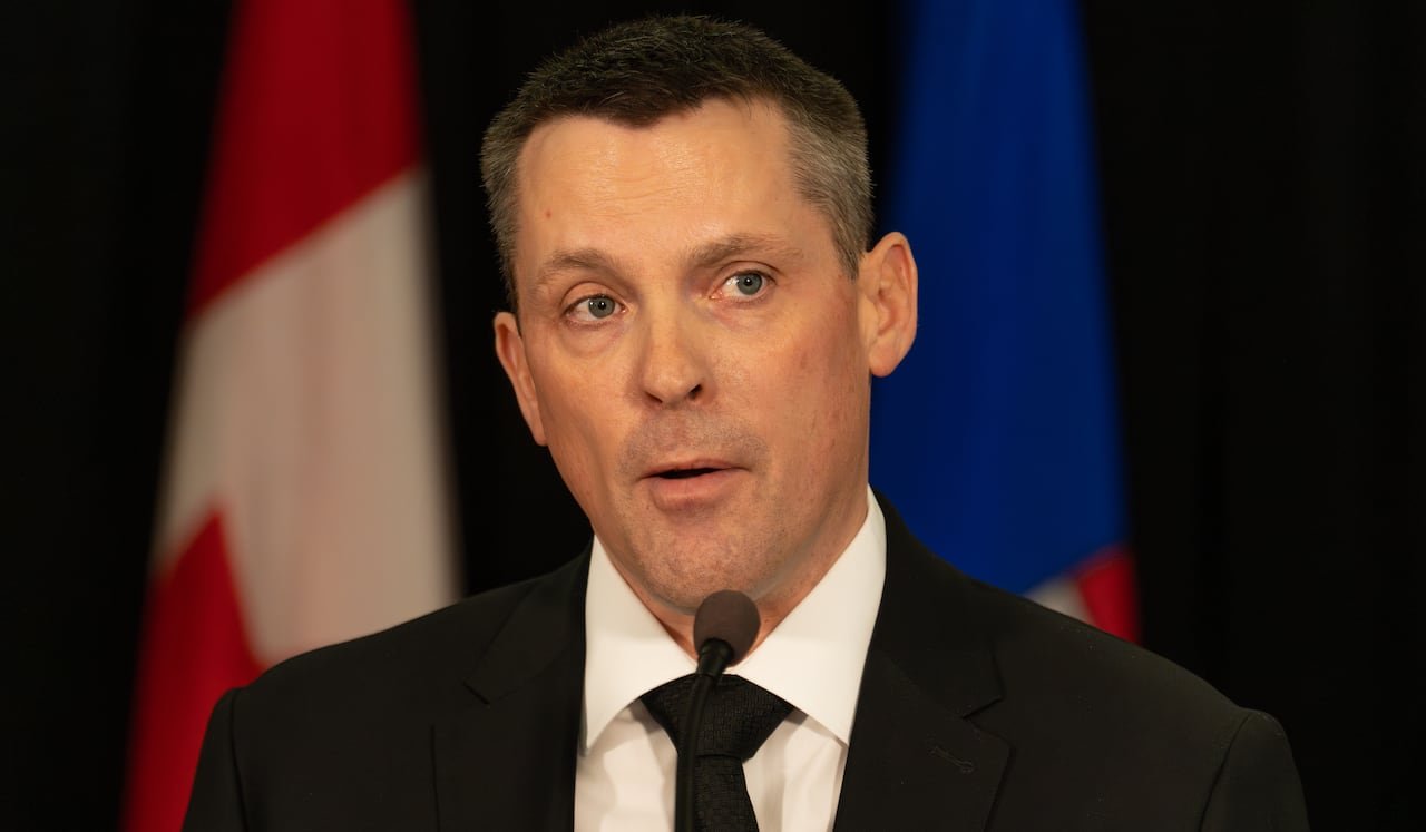 default-415 Close-up of a man standing in front of two flags.