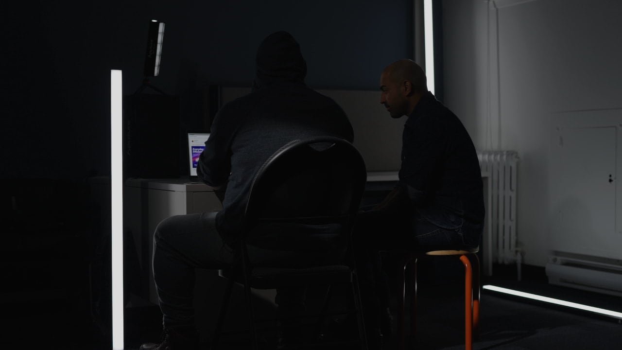default-413 Two men sit at a computer in a darkened room.